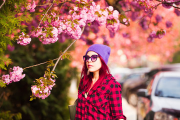 Girl with long colored hair posing near sakura branch