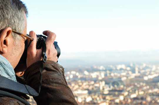 Caucasian middle-aged man photographer taking picture from the top of the famous sightseeing Basilica Fourvière in Lyon, France. View from the hill on the city.