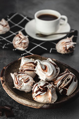 Still life composition, many white and chocolate meringues with coffee cup on grey cement background, food and homemade baking concept in rustic style