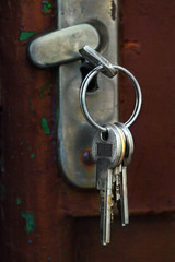 Old fashioned gate mortise lock with set of keys and one in the key hole. Detail on iron sashlock with silver keys on the keyring and one closing. Focus on keys. Closeup shot. House lock.