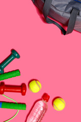 Tennis ball with dumbbells and bottle of water isolated on pastel pink background. Healthy lifestyle concept, fitness and sport with copy space for text.