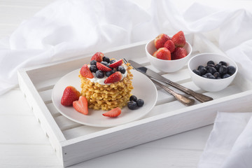 Delicious waffles with fresh fruit and berries on a white wooden table. Waffles with strawberries and blueberries. Free space for text. Traditional belgian waffles with fresh fruit. Stack of waffles w