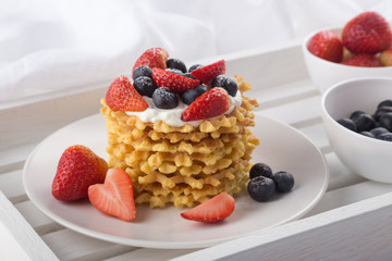 Delicious waffles with fresh fruit and berries on a white wooden table. Waffles with strawberries and blueberries. Free space for text. Traditional belgian waffles with fresh fruit. Stack of waffles w
