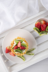 Delicious waffles with fresh fruit and berries on a white wooden table. Waffles with strawberries, kiwi, banana, cream. Free space for text. Traditional belgian waffles with fresh fruit. Stack of waff