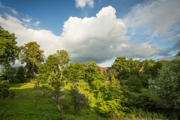 Obraz premium Scenic Summertime View of a Beautiful European rural Landscape Garden with a Green Lawn, Leafy Trees and nice sky with clouds. Czech Republic garden.