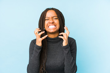 Young african american woman isolated on blue background upset screaming with tense hands.