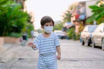 Child wearing a protective face mask on a city street with air pollution. Facial hygienic mask for Safety outdoor environmental awareness concept And protect disease virus against germs dustpm2.5