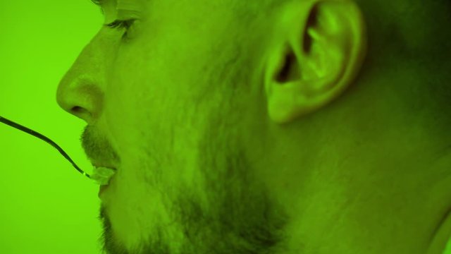 Close-up of a man with a beard who eats caesar salad from a fork. Caesar salad on a fork. The effect of color changes, changing color correction.