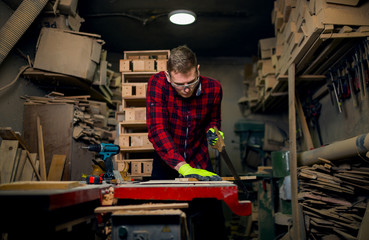 Craftsman using hand saw in wood workshop
