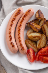 Close-up shot of fried potatoes with sausages and egg. Breakfast. Potatoes with sausages fried in oil, in rustic style. Frying pan with tasty cooked egg and sausages on table
