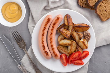 Close-up shot of fried potatoes with sausages and egg. Breakfast. Potatoes with sausages fried in oil, in rustic style. Frying pan with tasty cooked egg and sausages on table
