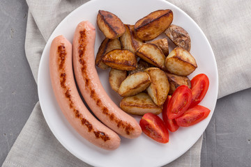 Close-up shot of fried potatoes with sausages and egg. Breakfast. Potatoes with sausages fried in oil, in rustic style. Frying pan with tasty cooked egg and sausages on table