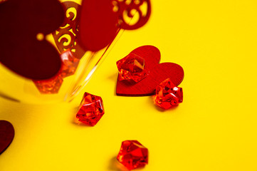 red crystals and hearts from a vase on a yellow background. composition of figures. Valentine's Day