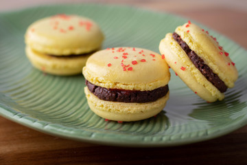Lemon Yellow Macaron Cookies with Chocolate Filling in Green Dish