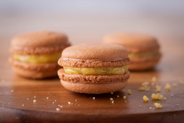 Chocolate Macarons with Lemon Yellow Filling on a Wood Counter