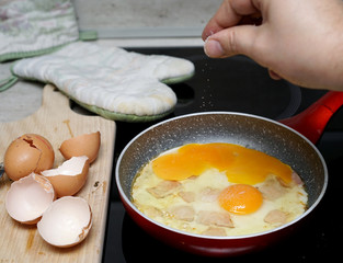 salting scrambled eggs while frying in a pan