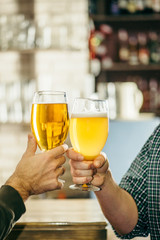 two people clink glasses with beer at the bar