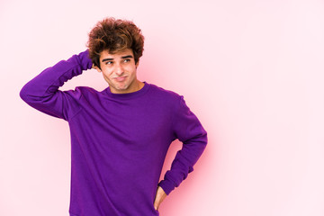 Young caucasian man against a pink background isolated touching back of head, thinking and making a choice.