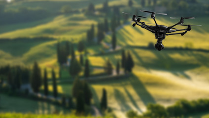 A flying drone with camera with blured hills of Tuscany in the background