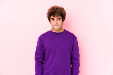 Young caucasian man against a pink background isolated confused, feels doubtful and unsure.