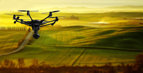 A flying drone with camera with blured hills of Tuscany in the background