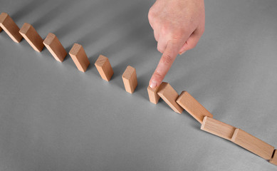 domino effect prevention concept. finger stops falling dominoes