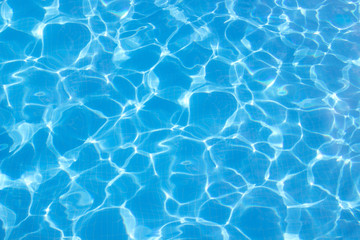 Fototapeta na wymiar blue pool water with waves and sun flare