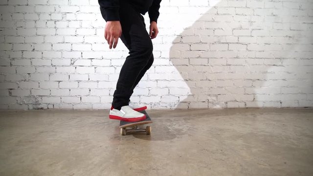 Skateboarder performing skateboard trick - kick flip on concrete. Athlete practicing jump on white background, preparing for competition. Extreme sport, youth culture