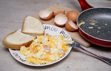 scrambled eggs and bread with butter on a plate immediately after preparation