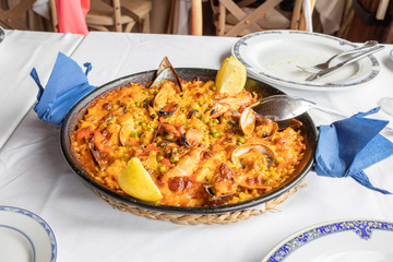 typical Spanish paella with seafood (mussel, prawn, lobster, squid, clam), rice and lemon ready to...