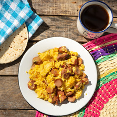 Scrambled eggs with sausage breakfast on wooden background