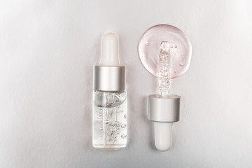 Bottle with hyaluronic acid on silver background. Concept of modern beauty. Flat lay style.