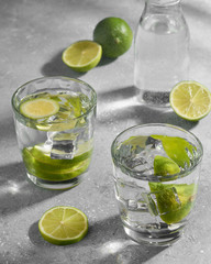 Water fitness detox with lime on a light grey background. Hard sun light and shadow. Soda coctail