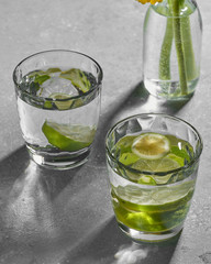 Water fitness detox with lime on a light grey background. Hard sun light and shadow. Soda coctail