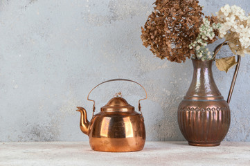 Vintage copper teapot on concrete background.