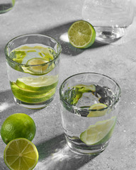 Water fitness detox with lime on a light grey background. Hard sun light and shadow. Soda coctail