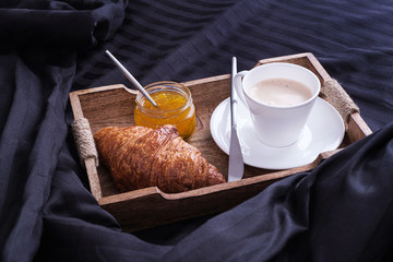 Breakfast in bed with coffee and croissants and jam