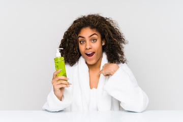 Young african american woman holding an aloe vera surprised pointing at himself, smiling broadly.