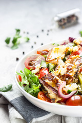 Vegetable salad cherry tomatoes, baked pepper, salad mix and onion with grilled haloumi (halloumi) cheese. Keto diet, healthy food. Light grey stone background. Close up.