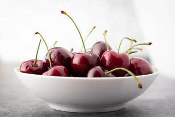 White Bowl of Fresh Cherries Against a Light Background