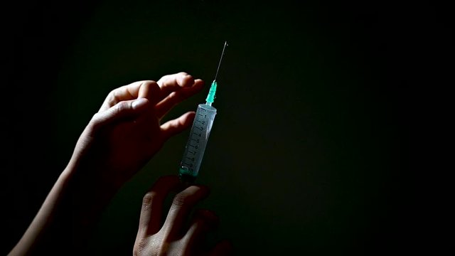 Nurse checking the 10ml syringle with liquid on dark background