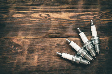 Spark plugs on brown wooden workbench background with copy space.
