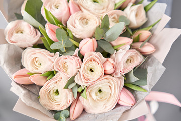 Bunch pale pink tulips and ranunculus flowers with green eucalyptus. The work of the florist at a flower shop.