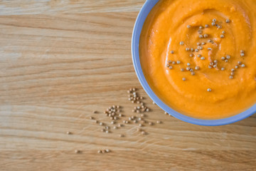 Top view of pumpkin soup in blue bowl on wooden background