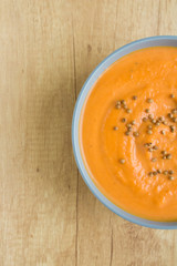 Top view of pumpkin soup in blue bowl on wooden background. Vertical photo. Copy space