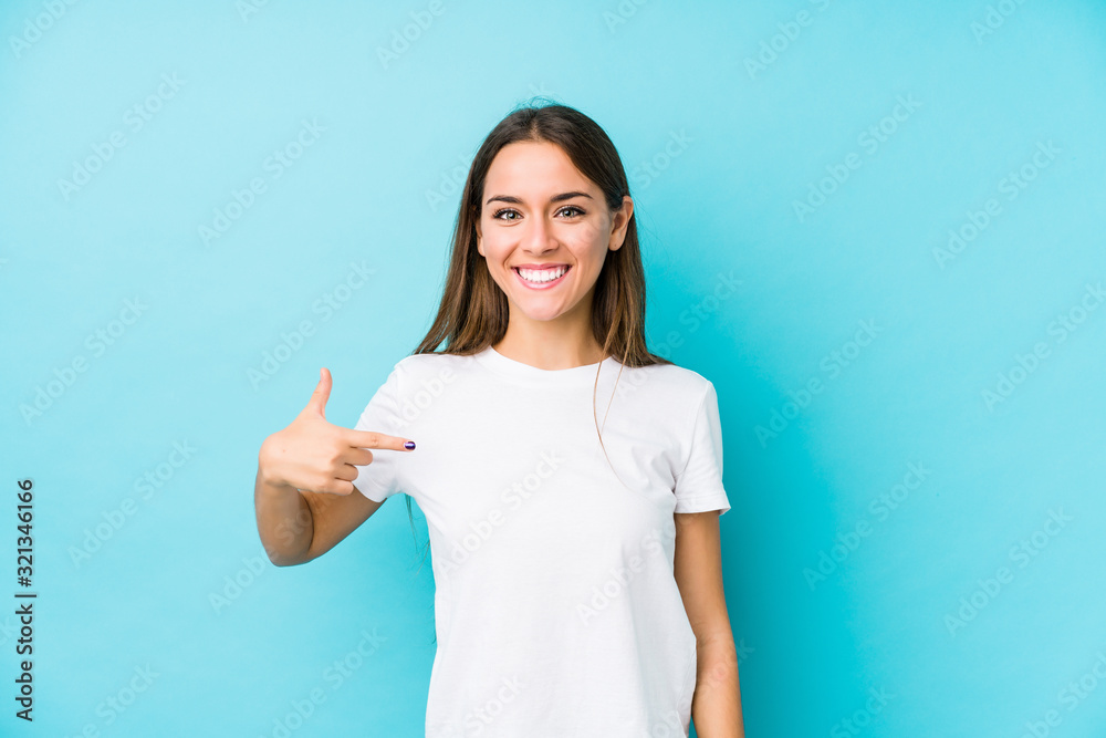 Wall mural young caucasian woman isolated person pointing by hand to a shirt copy space, proud and confident