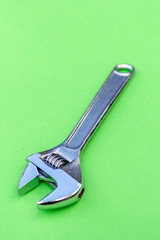 Adjustable wrench on green background