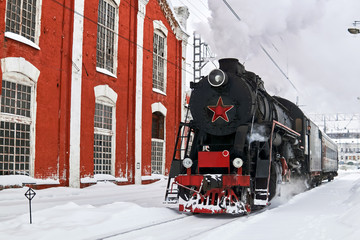 steam locomotive passing through train station in winter