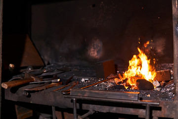 blacksmith furnace with burning fire and forging tools lying nearby