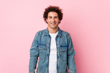 Curly mature man wearing a denim jacket against pink background happy, smiling and cheerful.